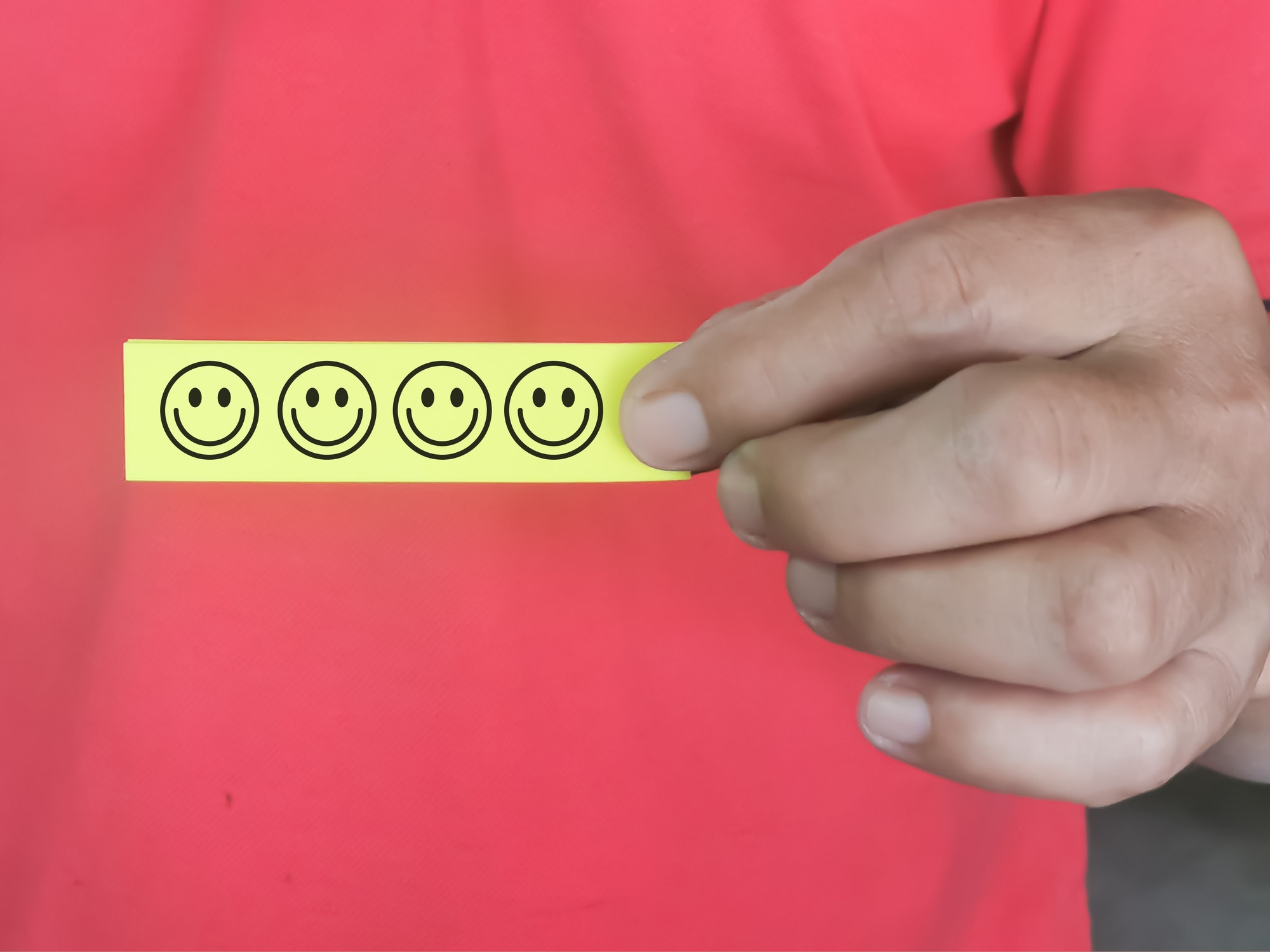 Selective focus sticky note with smiley face symbol hold by a man.